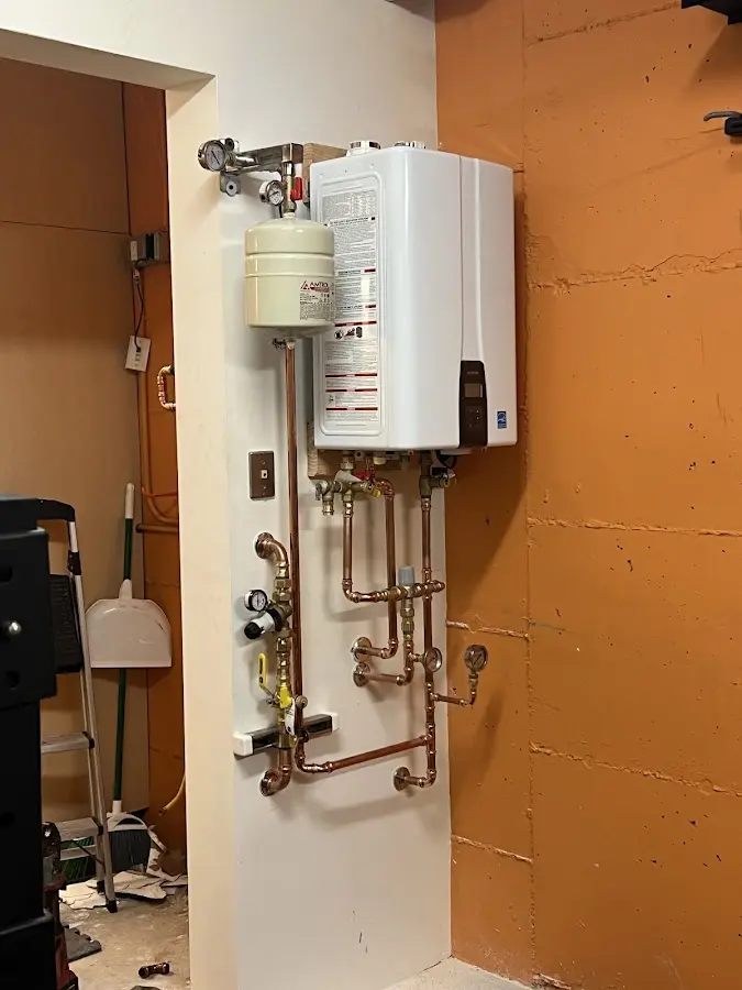 Plumbing technician inspecting water heater connections in Taylors